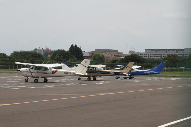 Three small airplanes, one white and red, one yellow, and one blue, are parked on an airfield.